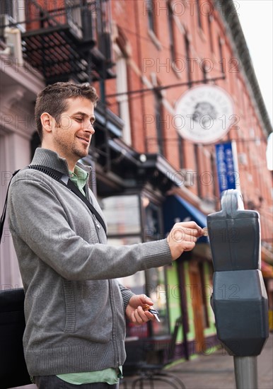 Man inserting coin to parking meter. Photo : Daniel Grill