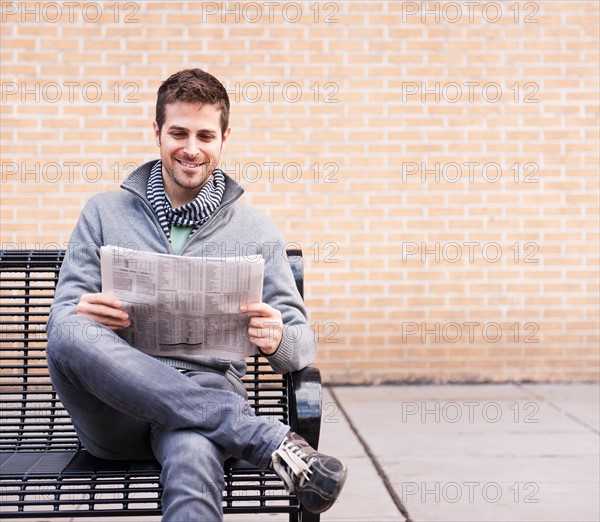 Man on bench reading newspaper. Photo : Daniel Grill