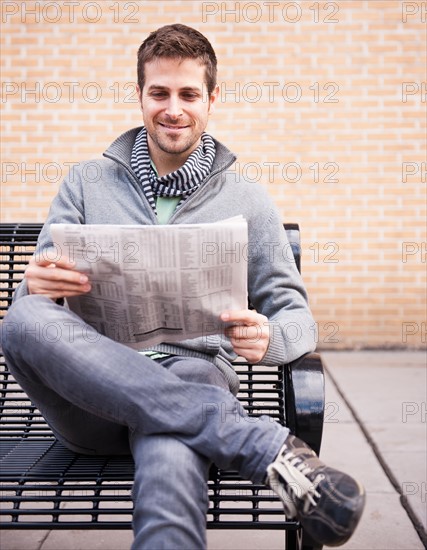 Man on bench reading newspaper. Photo : Daniel Grill