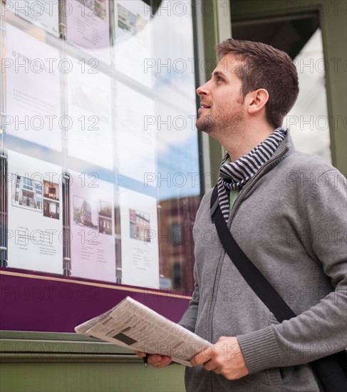 Man with newspaper looking at advert display. Photo : Daniel Grill