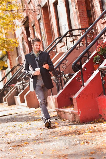 Man walking with mobile phone and coffee. Photo: Daniel Grill
