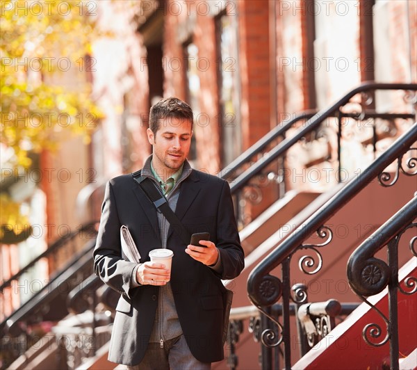 Man walking with mobile phone and coffee. Photo: Daniel Grill