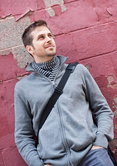 Man standing at front of old peeling red wall. Photo: Daniel Grill