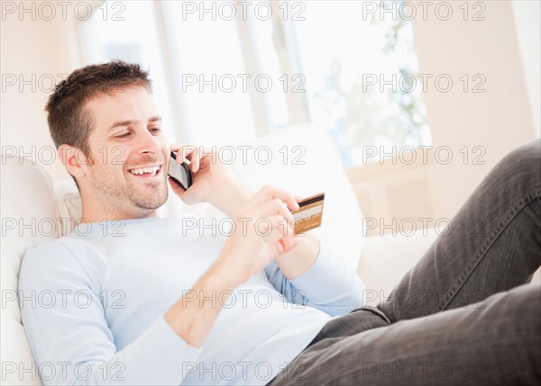 Man talking on mobile and holding credit card. Photo: Daniel Grill