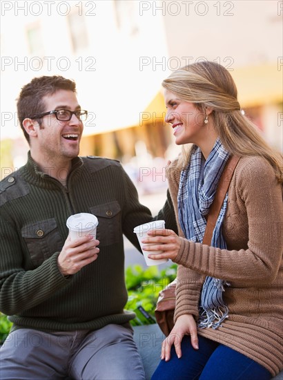 Young couple sitting with take-away coffee. Photo : Daniel Grill