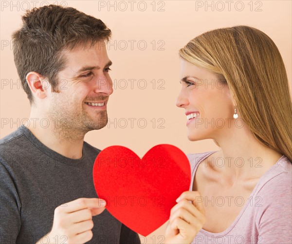 Couple holding red paper heart. Photo : Daniel Grill