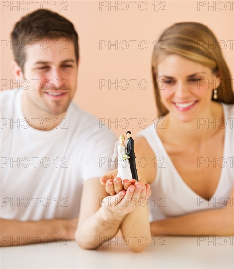 Couple holding small wedding figurine. Photo : Daniel Grill