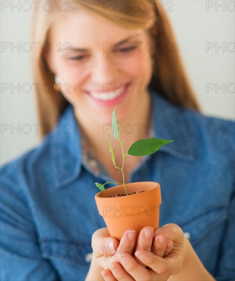 Young woman holding small plant. Photo : Daniel Grill