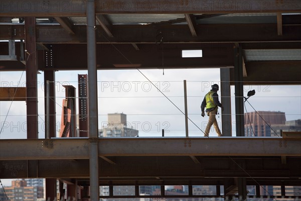 USA, New York City, Construction worker walking inside of unfinished structure. Photo: fotog