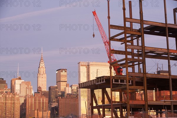 USA, New York City, Crane with unfinished structure and Manhattan skyline in background. Photo : fotog