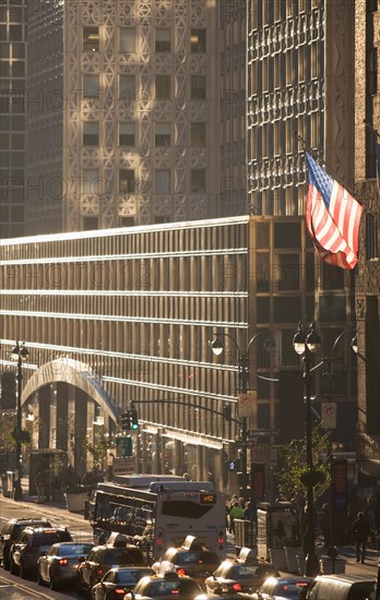 USA, New York City, Street scene with american flag flying outside office building. Photo: fotog