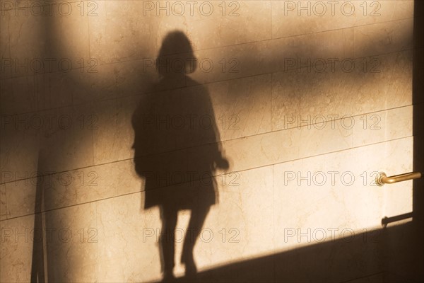 Shadow of single male pedestrian on sunlit wall. Photo : fotog