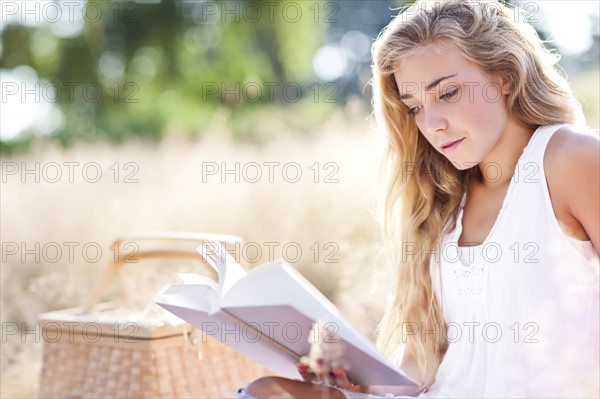 Teenage girl (16-17) reading book outdoors. Photo : Take A Pix Media