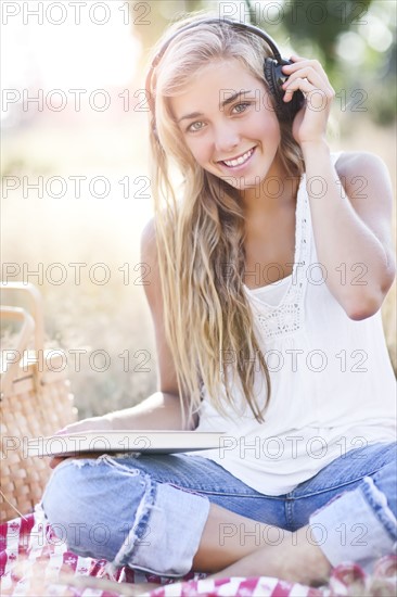 Teenage girl (16-17) posing with book and headphones on. Photo : Take A Pix Media