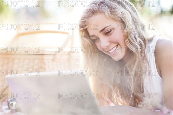 Happy teenage girl (16-17) using laptop outdoors. Photo: Take A Pix Media
