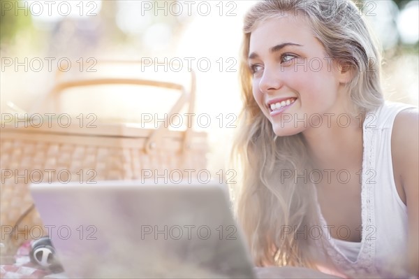 Happy teenage girl (16-17) using laptop outdoors. Photo: Take A Pix Media