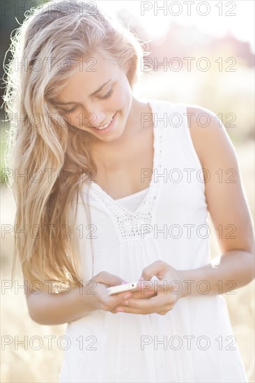 Teenage girl (16-17) text messaging outdoors. Photo: Take A Pix Media