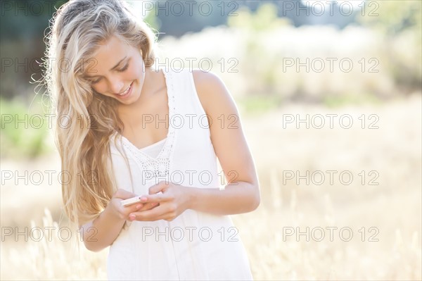 Teenage girl (16-17) text messaging outdoors. Photo: Take A Pix Media