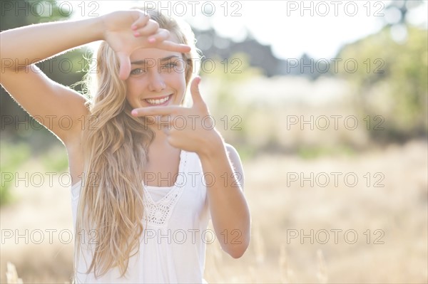 Teenage girl (16-17) displaying finger frame. Photo : Take A Pix Media