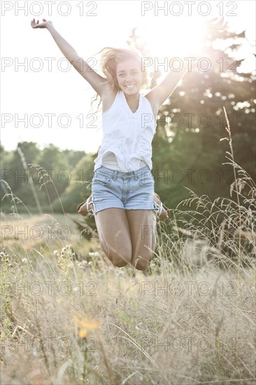 Happy teenage girl (16-17) jumping in bright sunshine. Photo : Take A Pix Media