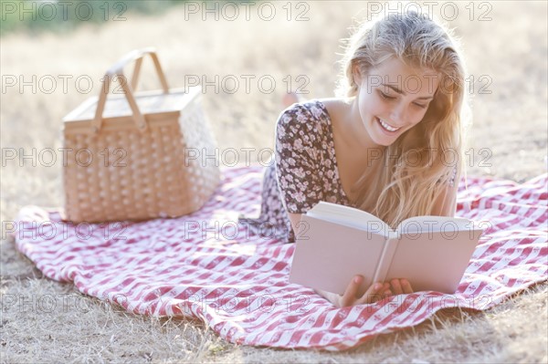 Happy teenage girl (16-17) reading book outdoors. Photo: Take A Pix Media