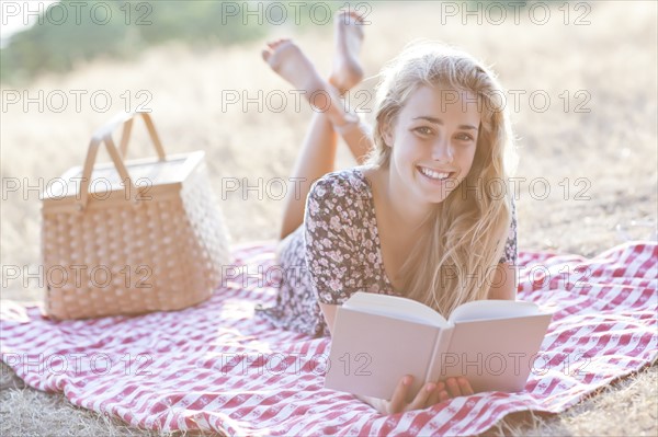 Happy teenage girl (16-17) reading book outdoors. Photo: Take A Pix Media