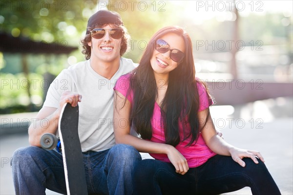 Young multi-racial couple posing with skateboard. Photo: Take A Pix Media