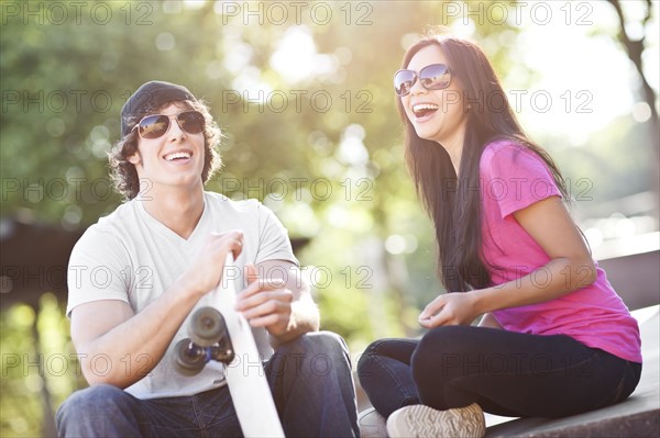 Young multi-racial couple posing with skateboard. Photo : Take A Pix Media