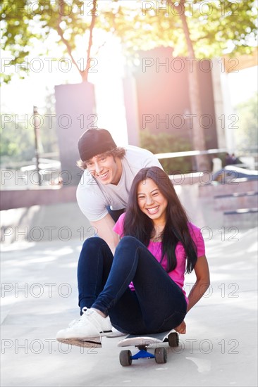 Young multi-racial couple playing with skateboard. Photo : Take A Pix Media