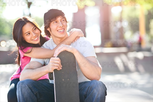 Young multi-racial couple posing with skateboard. Photo : Take A Pix Media