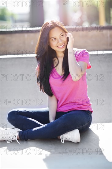 Young chinese woman using mobile phone outdoors. Photo : Take A Pix Media