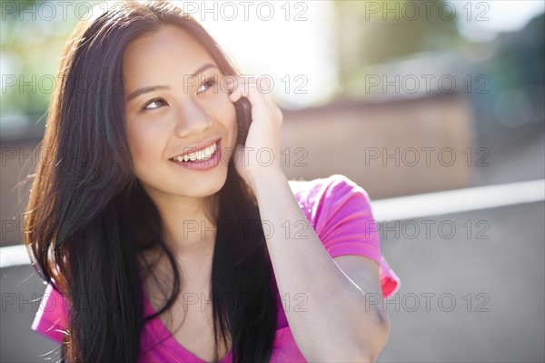 Young chinese woman using mobile phone outdoors. Photo: Take A Pix Media