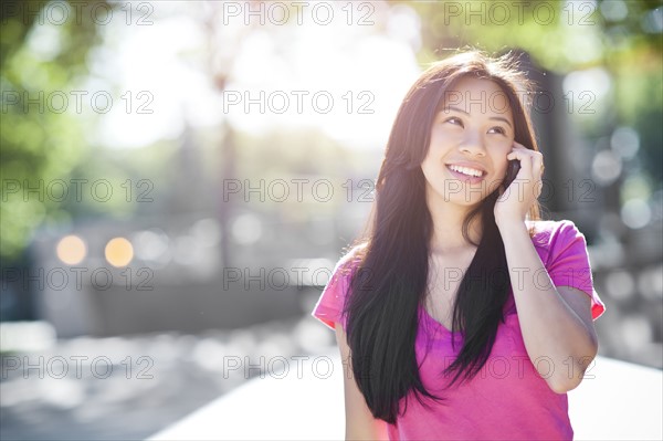 Young chinese woman using mobile phone outdoors. Photo : Take A Pix Media