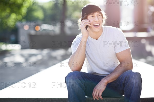 Young man using mobile phone outdoors. Photo : Take A Pix Media