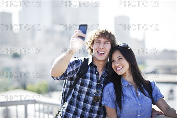 USA, Washington, Seattle, Couple wearing sunglasses photographing themselves with smart phone. Photo: Take A Pix Media