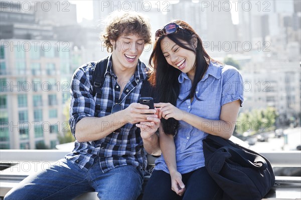USA, Washington, Seattle, Couple looking at mobile phone. Photo: Take A Pix Media