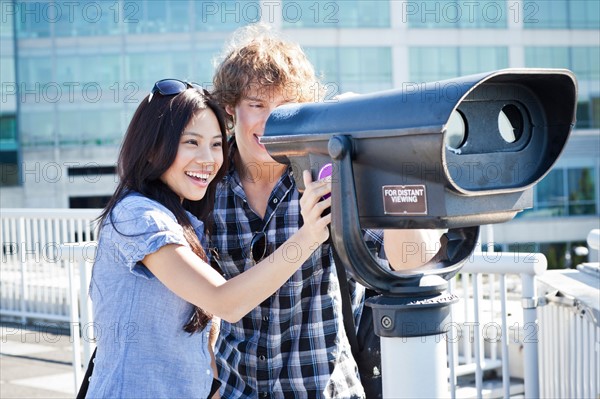 USA, Washington, Seattle, Couple looking through coin-operated binoculars. Photo : Take A Pix Media