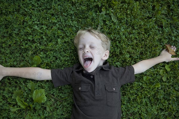 Boy (4-5) lying on lawn laughing. Photo: Johannes Kroemer