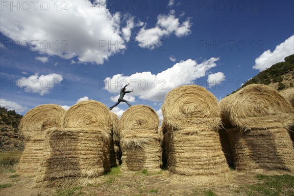 USA, Colorado, Woman jumping on haystacks. Photo: John Kelly