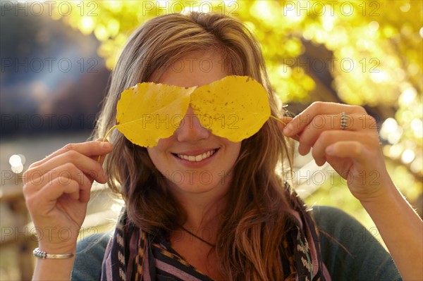Woman covering eyes with autumn leaves. Photo: John Kelly