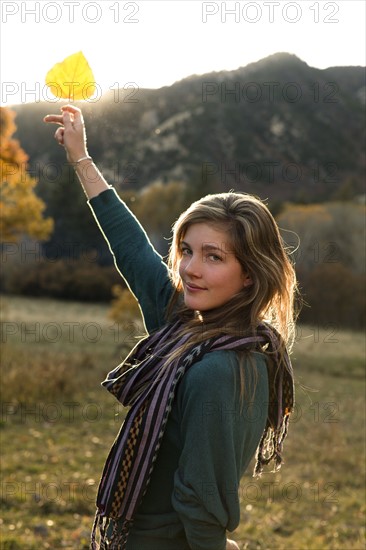 USA, Colorado, Portrait of young woman holding up leaf. Photo: John Kelly
