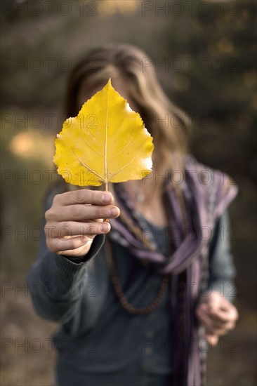 Woman holding leaf in front of face. Photo : John Kelly