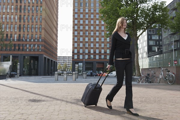 The Netherlands, Amsterdam, Businesswoman walking with luggage. Photo : Jan Scherders