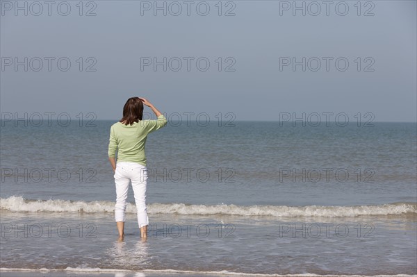 Woman on beach looking out to sea. Photo : Jan Scherders