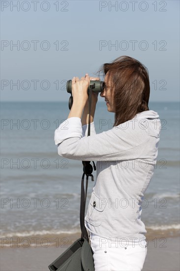 Woman on beach looking through binoculars. Photo: Jan Scherders