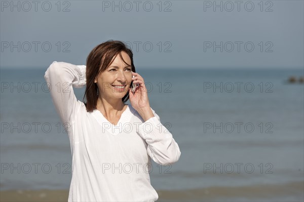 Woman on beach talking on phone. Photo: Jan Scherders