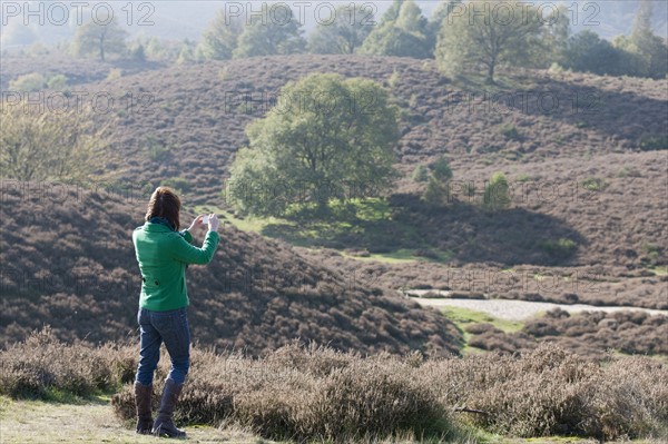The Netherlands, Veluwezoom, Posbank, Woman using camera in countryside. Photo : Jan Scherders