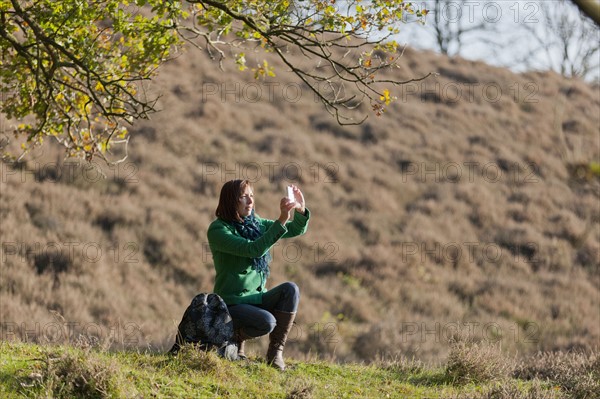 The Netherlands, Veluwezoom, Posbank, Hiker using camera in countryside. Photo: Jan Scherders