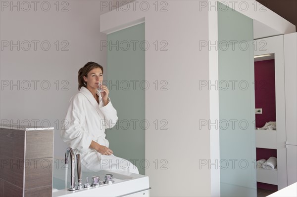 Woman in bathrobe sitting on tub. Photo : Jan Scherders