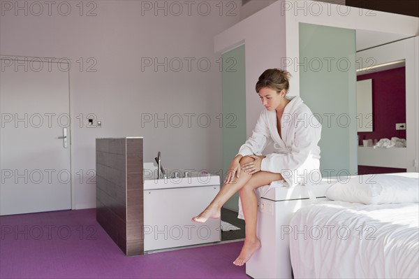 Woman shaving legs in bedroom. Photo : Jan Scherders